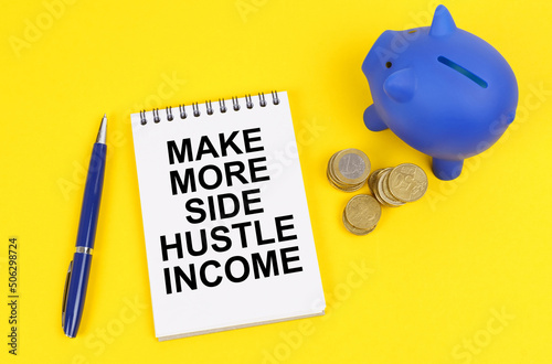 On a yellow surface, a piggy bank, coins and a notepad with the inscription - Make more side hustle income photo