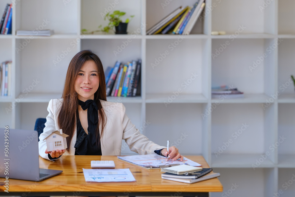 Asian woman accountant, business woman, real estate agent, holding a pen, pointing at home loan and interest documents to calculate the risk in the home investment budget. Asian woman accountant, business woman, real estate agent, holding a pen, pointing at home loan and interest documents to calculate the risk in the home investment budget.