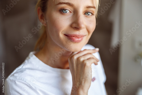 Face of young attractive Caucasian woman touching chin with hand and smiling. Portrait. photo