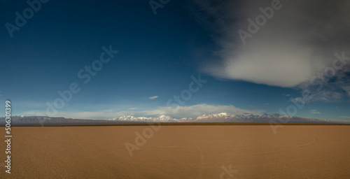 Panorama view of the arid desert in Barreal Blanco, in San Juan, Argentina. The Andes mountains in the horizon under a deep blue sky.	