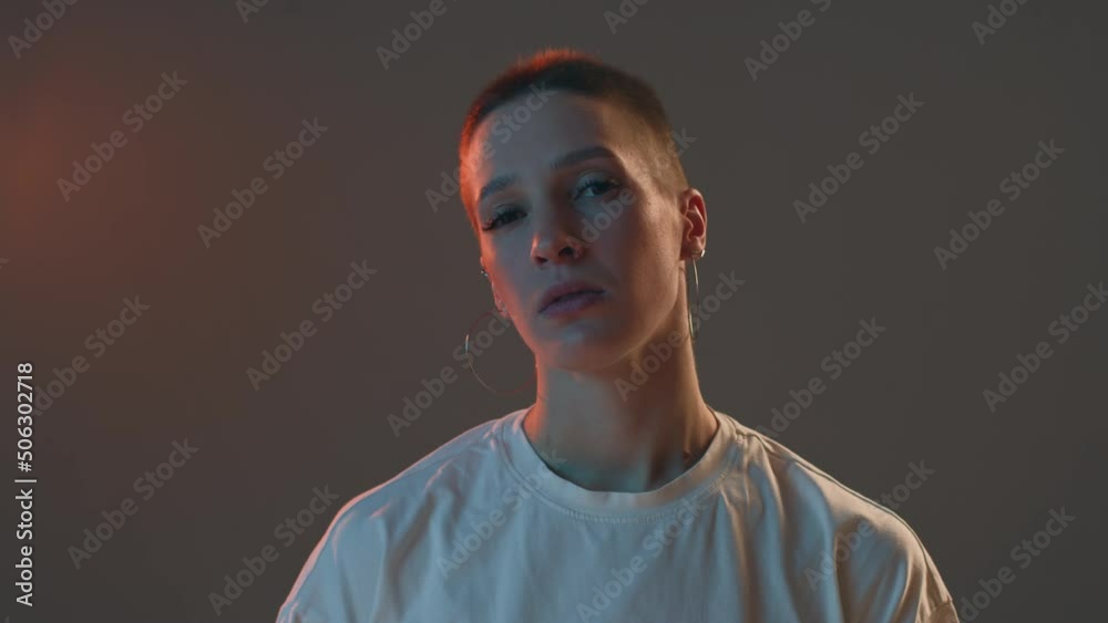 Stylish pensive american girl with short haircut wearing unisex white t-shirt look at camera in studio, headshot. ProRes Stylish pensive american girl with short haircut wearing unisex white t-shirt look at camera in studio, headshot. ProRes