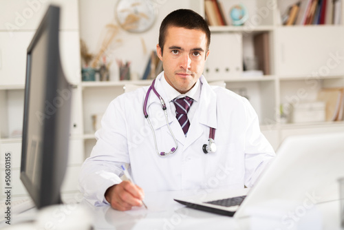 Cheerful man doctor working effectively in her office