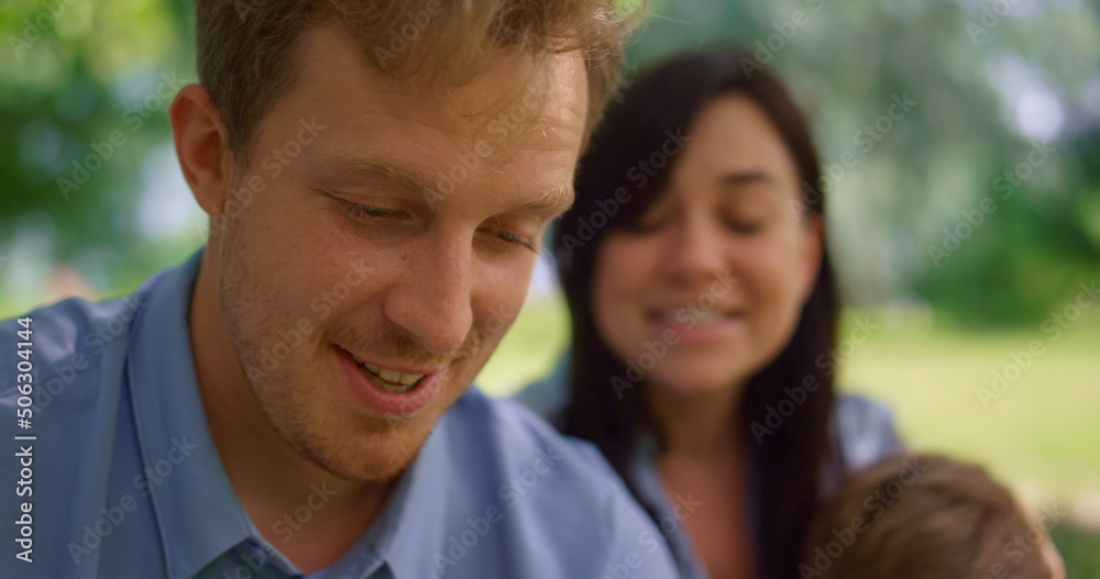 Young couple watching tablet on nature close up. Happy family have fun on picnic Young couple watching tablet on nature close up. Happy family have fun on picnic