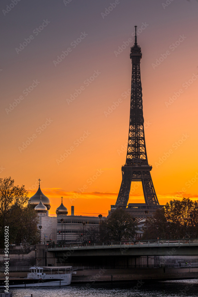Paris, France - November 6, 2020: Eiffel tower and Saint-Trinite Orthodox Cathedral at sunset in Paris