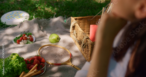 Woman sitting on picnic blanket with diverse snacks blurred view close up. 