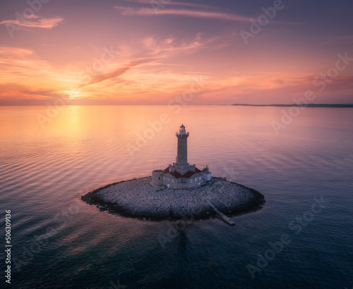 Fotografia, Obraz Lighthouse on smal island in the sea at colorful sunset in summer