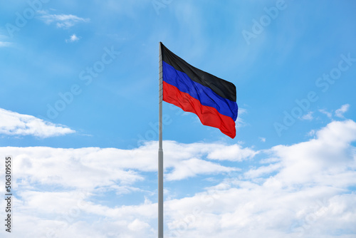 Flag of the self-proclaimed Donets People's Republic (DPR or DNR) is waving in front of blue sky and clouds
