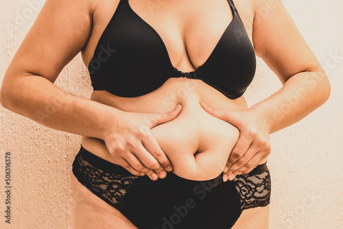 Cuerpo de mujer gorda en ropa interior agarrando su barriga, panza. Cuerpo diverso. photo