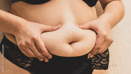 Fotografia Detalle, manos de mujer agarrando su barriga, panza. Gordura.