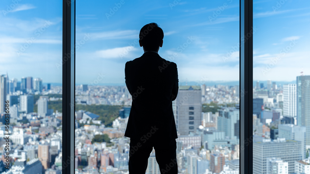 Fototapeta premium 高層ビルを眺めるビジネスマンの背中