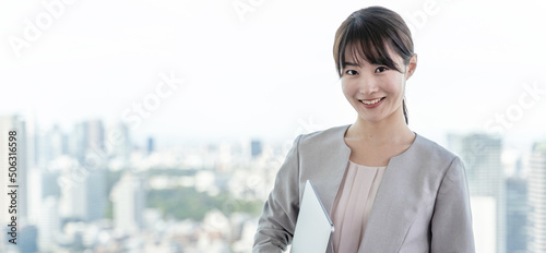 高層ビルを背景に立つビジネスウーマンのポートレート
