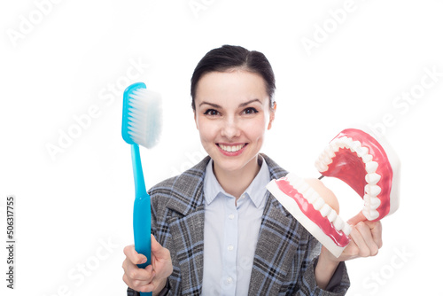 happy woman in office suit holding big toothbrush and big jaw mockup with teeth, white background