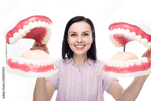 happy woman with perfect smile holding two huge dental jaws in her hands, white background