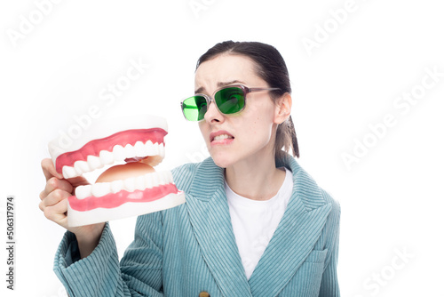 woman in green glasses lovingly looks at the dental jaw, white background
