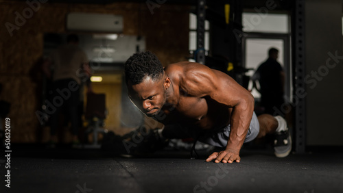 African american man doing one arm push ups in the gym. 