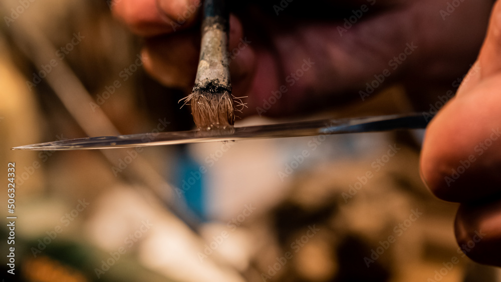 A master swordsmith is applying oil to the knife blade in Japan. A master swordsmith is applying oil to the knife blade in Japan.