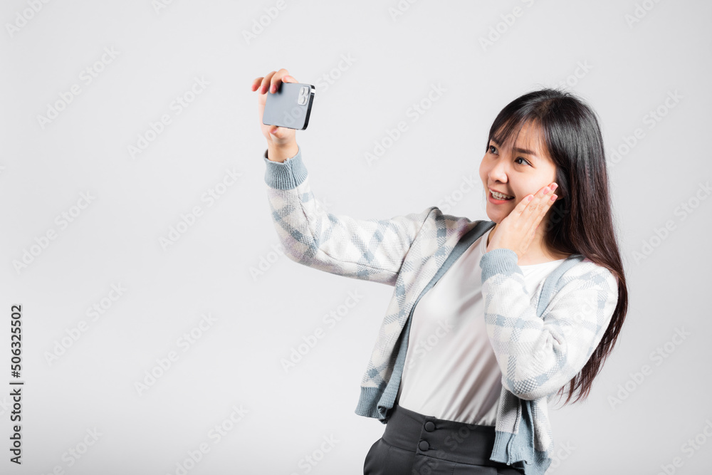 Woman excited holding smartphone to shooting selfie photo front camera studio shot isolated white background, happy young female smiling taking photography by mobile phone on mobile phone Woman excited holding smartphone to shooting selfie photo front camera studio shot isolated white background, happy young female smiling taking photography by mobile phone on mobile phone