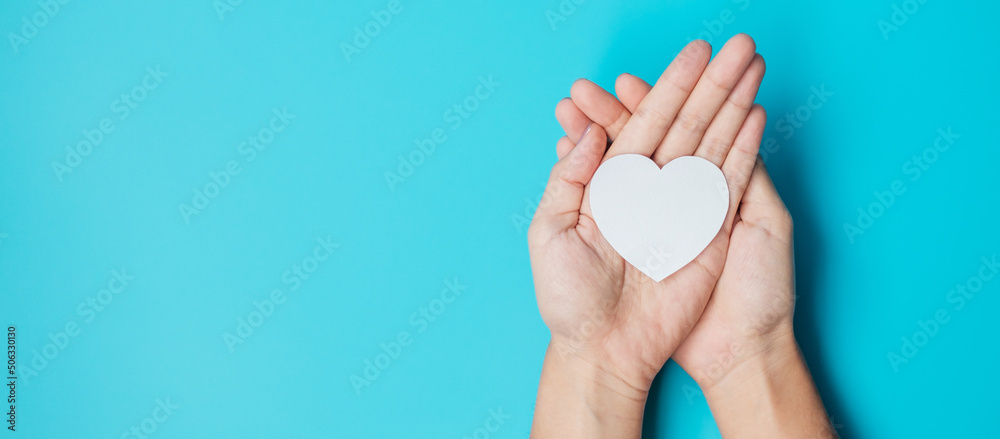 hands holding paper Heart on blue background. Donation, Wellness, world Heart day, world Health day and Happy Valentines day concepts