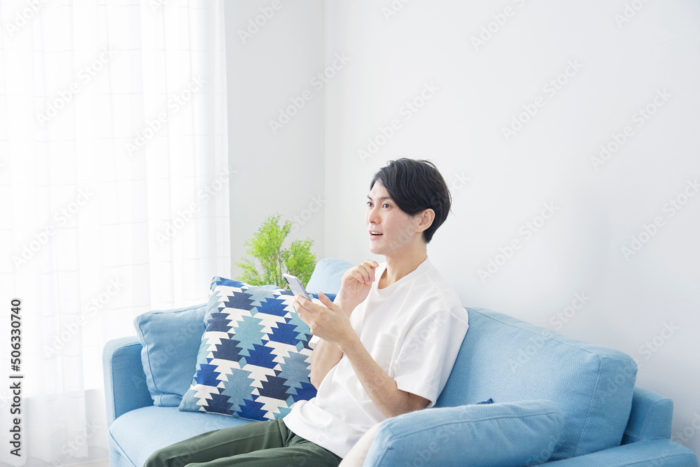 リビングでスマホを持って想像する男性