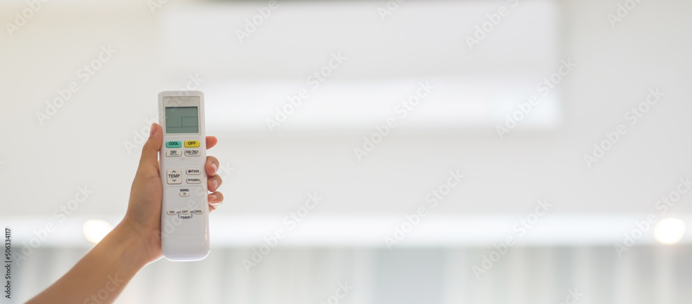 hand using remote controller for adjust Air conditioner inside the room of office or home