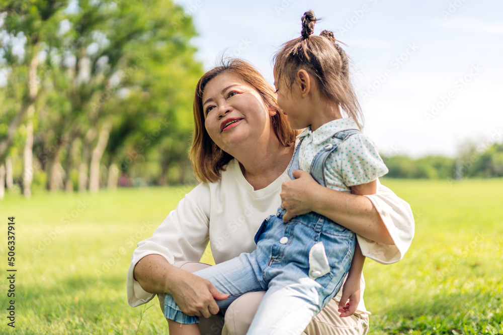 Portrait of happy love asian grandmother and little asian cute girl enjoy relax in summer park.Young girl with their laughing grandparent smiling together.Family and togetherness Portrait of happy love asian grandmother and little asian cute girl enjoy relax in summer park.Young girl with their laughing grandparent smiling together.Family and togetherness