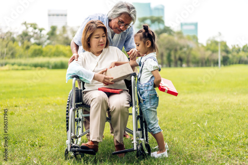 Portrait of happy love asian grandfather with grandmother and asian little cute girl enjoy relax in summer park.Young girl with their laughing grandparents smiling together.Family and togetherness