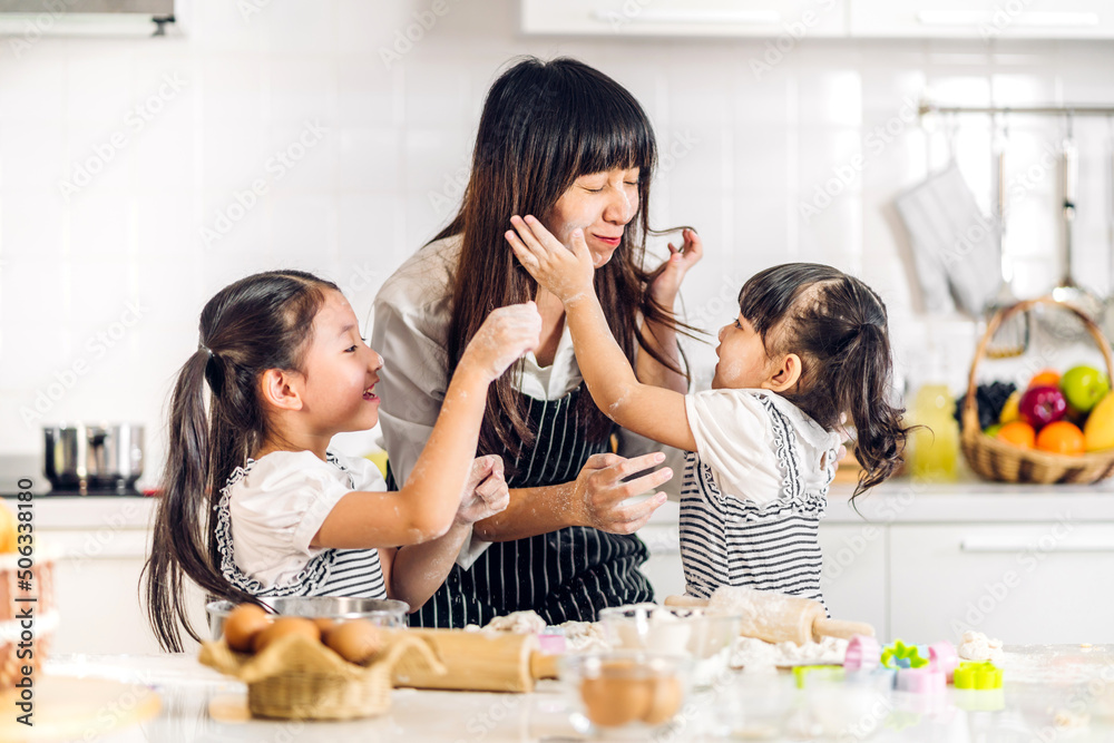 Portrait of enjoy happy love asian family mother and little toddler asian girl daughter child having fun cooking together with dough for homemade bake cookie and cake ingredient on table in kitchen Portrait of enjoy happy love asian family mother and little toddler asian girl daughter child having fun cooking together with dough for homemade bake cookie and cake ingredient on table in kitchen