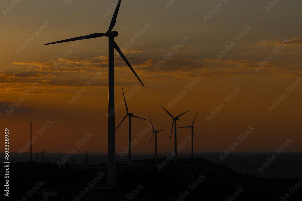 Obraz premium Sunset over a windmill park. An example of renewable energy, clean nature and a sustainable future. Earth Day
