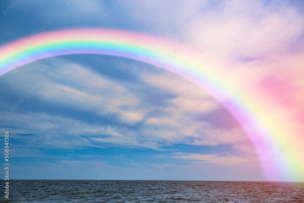 Beautiful view of colorful rainbow in sky over sea Beautiful view of colorful rainbow in sky over sea