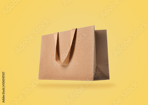 Kraft paper bag on yellow background. Mockup for design