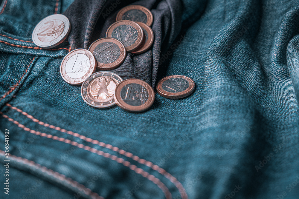 Symbol for crisis or cost of living or bankruptcy. Coins of one and two euros spilling out of an inside-out jeans pocket Symbol for crisis or cost of living or bankruptcy. Coins of one and two euros spilling out of an inside-out jeans pocket