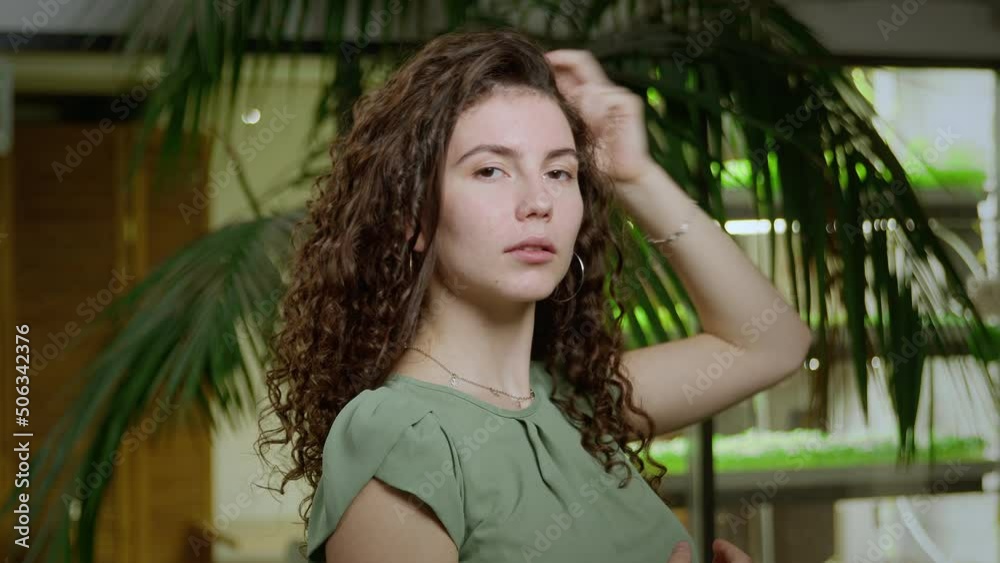 Close-up of a young woman with brown curly hair posing for the camera. Portrait of a girl Close-up of a young woman with brown curly hair posing for the camera. Portrait of a girl
