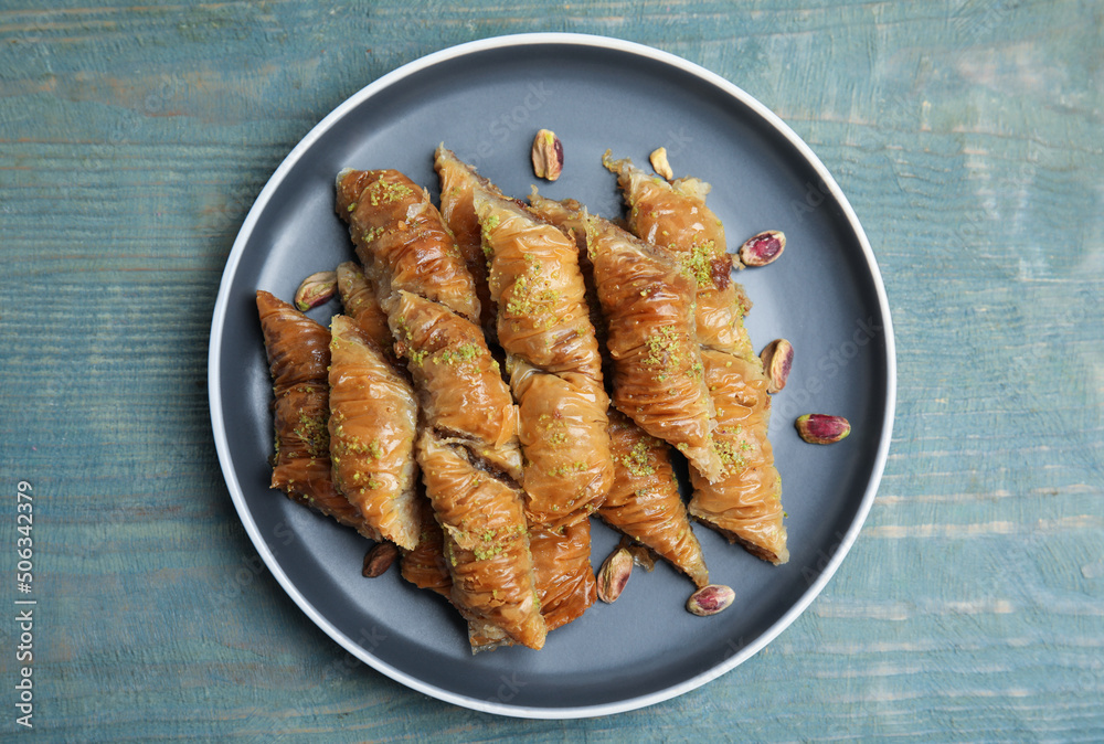 Delicious baklava with pistachio nuts on light blue wooden table, top view Delicious baklava with pistachio nuts on light blue wooden table, top view