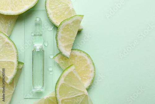 Pharmaceutical ampoule with medication and lime slices on turquoise background, flat lay. Space for text
