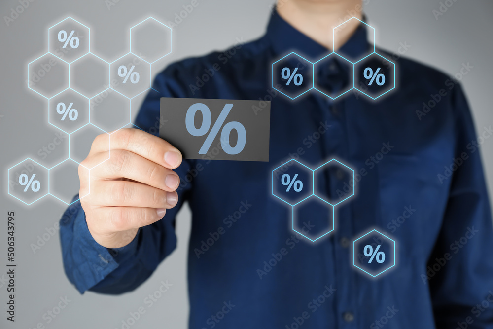 Man showing business card with percent sign on light grey background, closeup. Discount concept Man showing business card with percent sign on light grey background, closeup. Discount concept