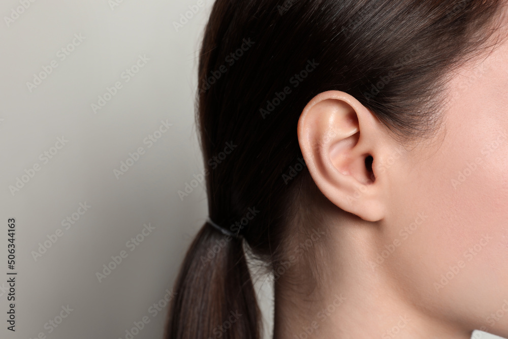 Woman on light background, closeup of ear. Space for text Woman on light background, closeup of ear. Space for text