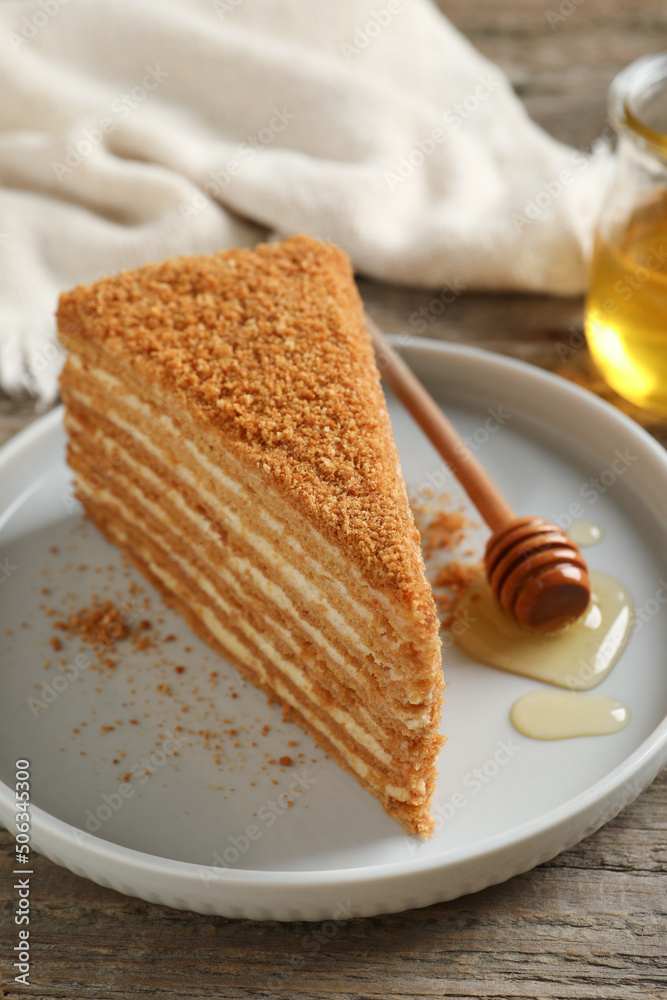 Slice of delicious layered honey cake served on wooden table, closeup Slice of delicious layered honey cake served on wooden table, closeup