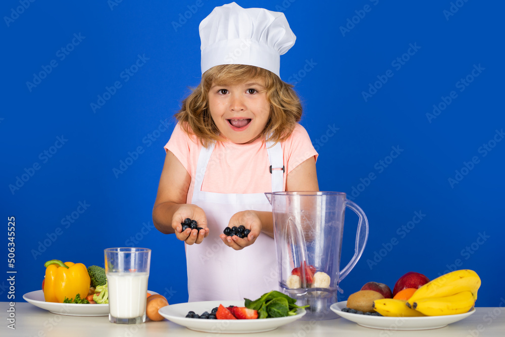 Excited funny chef cook. Child chef dressed cook baker apron and chef hat cooking blueberries smoothie isolated on studio background. Healthy nutrition kids food. Excited funny chef cook. Child chef dressed cook baker apron and chef hat cooking blueberries smoothie isolated on studio background. Healthy nutrition kids food.