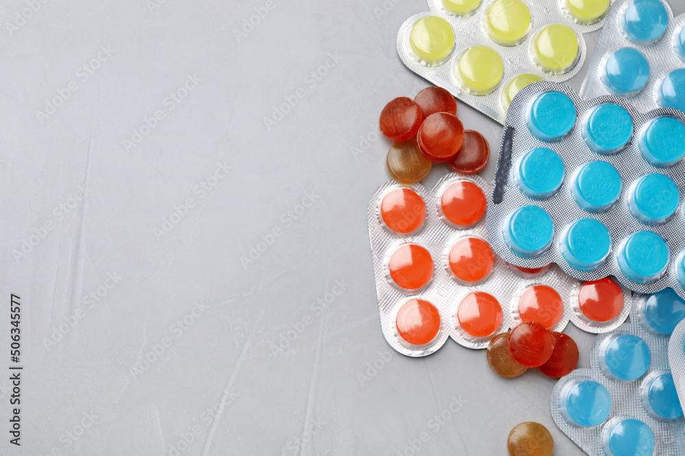 Colorful cough drops on grey background, flat lay. Space for text