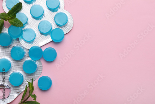 Many light blue cough drops and mint on pink background, flat lay. Space for text