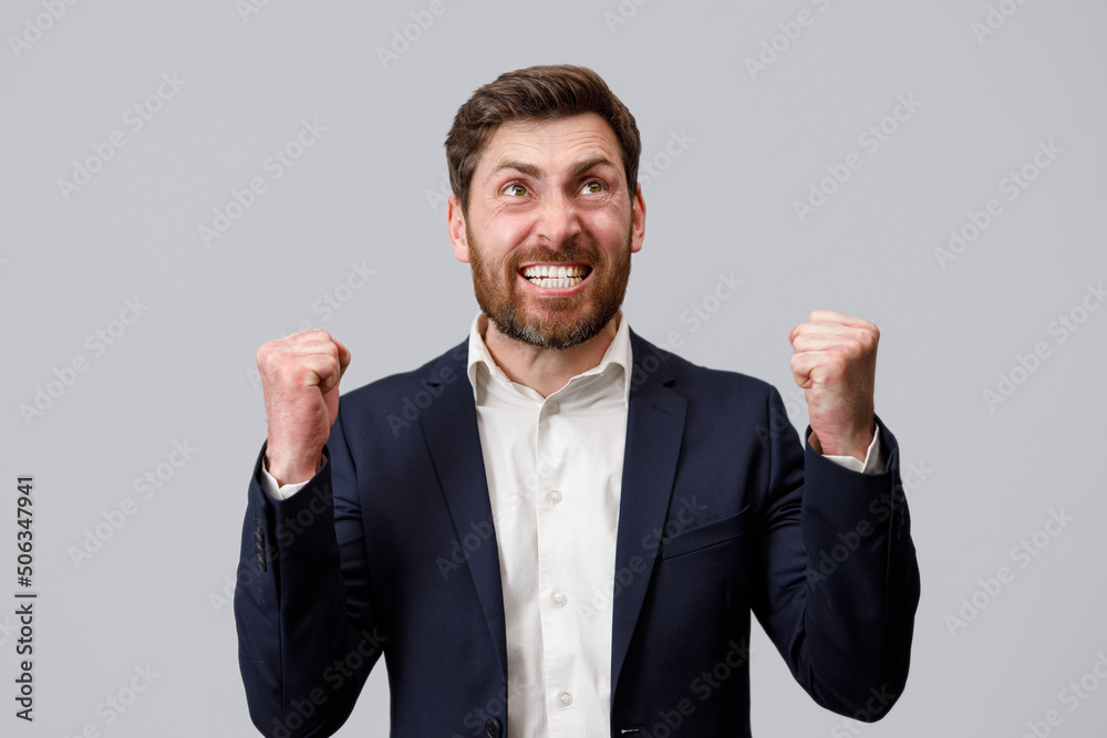 Happy joyful businessman wearing suit doing winner gesture clenching fists Happy joyful businessman wearing suit doing winner gesture clenching fists
