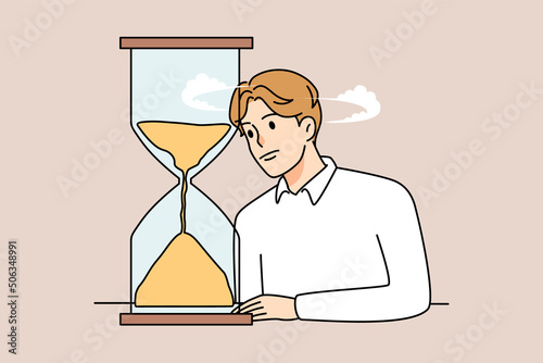 Bored man look at hourglass waiting 