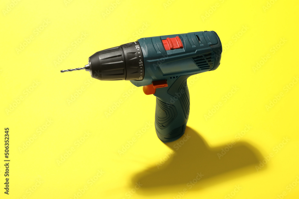 Modern electric power drill on yellow background