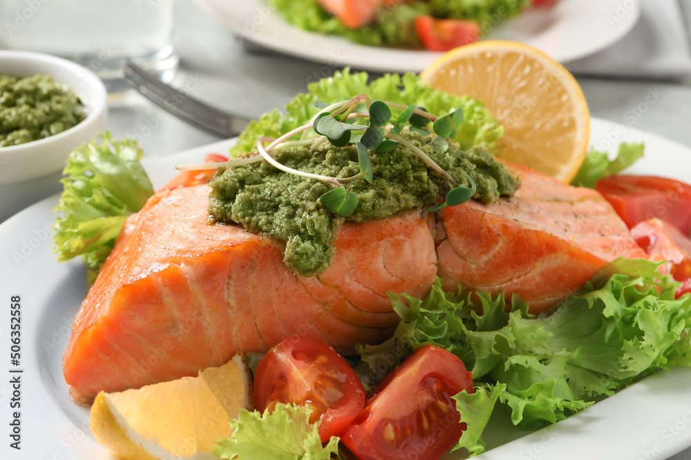 Tasty cooked salmon with pesto sauce and fresh salad on plate, closeup Tasty cooked salmon with pesto sauce and fresh salad on plate, closeup
