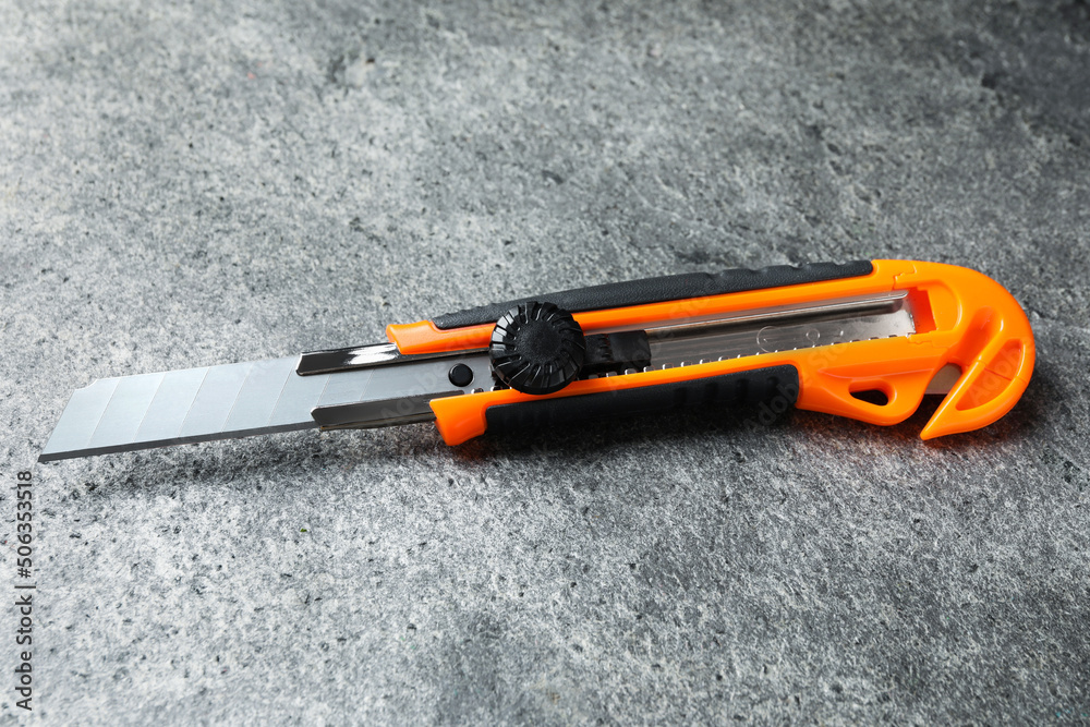 Orange utility knife on grey table. Construction tool Orange utility knife on grey table. Construction tool