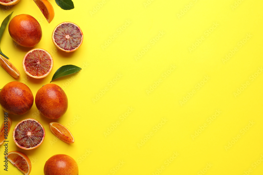 Many ripe sicilian oranges and leaves on yellow background, flat lay. Space for text Many ripe sicilian oranges and leaves on yellow background, flat lay. Space for text