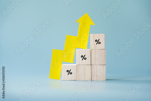 Yellow paper cut arrow going up positive trend on wooden blocks with percentages. Concept of profit increasing in percentage.