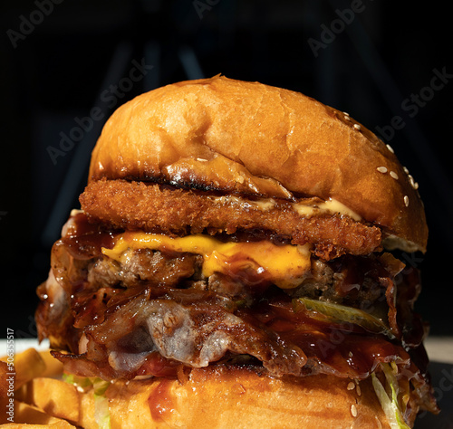 Tasty grilled burger with with beef, cheese, vegetables. Delicious grilled Cheeseburger on a dark background.