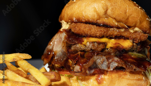 Tasty grilled burger with with beef, cheese, vegetables. Delicious grilled Cheeseburger on a dark background.
