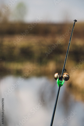 The bell alarm is on the fishing rod spinning in nature. bell lodge on a spinning rod over the river © Александр Маринич